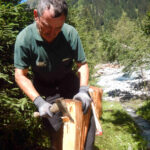 Photo: Mann in Wald, spaltet mit einer Axt Schindeln